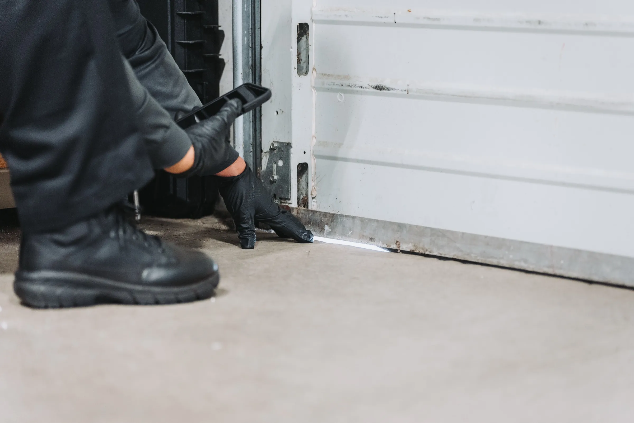 An A&A Pest Control technician pointing out the light showing through the gap under a roll-up door, a rodent entry point